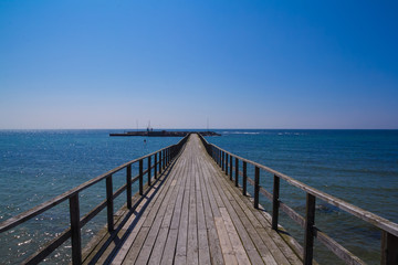 Very long wooden pier leading out on Østersøen from Arnager on Bornholm