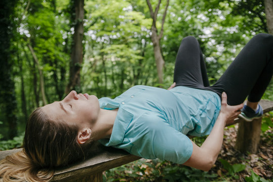 Young woman relaxing on bench in forest