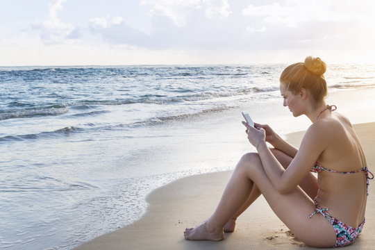 Dominican Rebublic, Young woman on tropical beach using mobile device