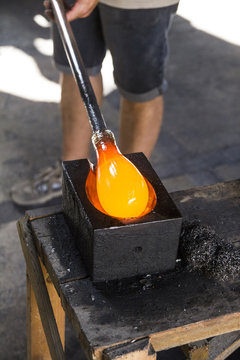 Man putting molten glass in a mold in a glass factory