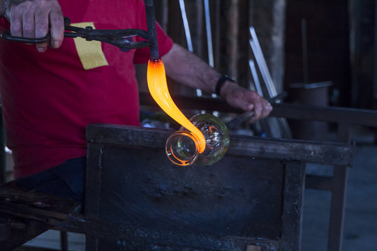 Man working with molten glass in a glass factory
