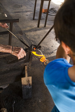 Men working with molten glass in a glass factory