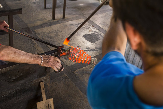 Men working with molten glass in a glass factory