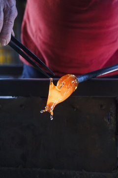 Man working with molten glass using a tweezers in a glass factory