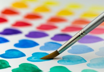Fototapeta premium Painting watercolor hearts with a paintbrush. Shallow depth of f