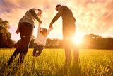 Parents hold the baby's hands.  Happy family in the park evening