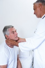 Obraz premium Male doctor examining senior mans neck
