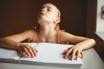 Blind girl using both hands to read braille