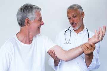 Male doctor giving palm acupressure treatment to senior man