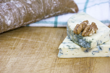 Two tasty pieces of cheese roquefort with bread and walnut on wooden background