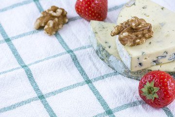 Two pieces of blue cheese roquefort with walnuts and strawberries on the towel