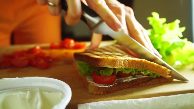 Young woman splitting sandwich with a knife