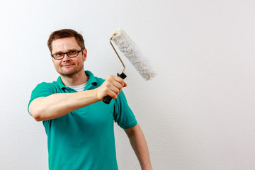 Mann streicht Wand weiß an, closeup
