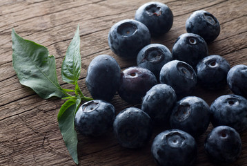 Freshly picked blueberries in wooden background. Juicy and fresh blueberries with green leaves on rustic table.Concept for healthy eating and nutrition