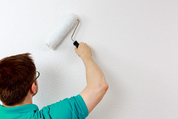 Mann streicht Wand weiß an, closeup