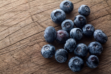 Freshly picked blueberries in wooden background. Juicy and fresh blueberries with green leaves on rustic table.Concept for healthy eating and nutrition