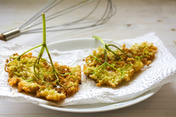 fried elderflowesr in pancake batter on a  paper towel, traditional dessert