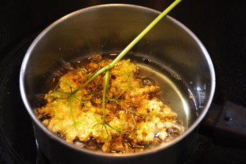frying elderflower in pancake batter in a small pot of boiling oil