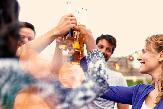 Multi-ethnic Millenial Group Of Friends Partying And Enjoying A Beer On Rooftop Terrasse At Sunset