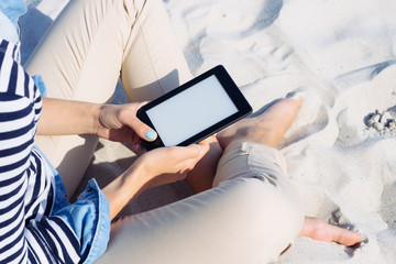 Cropped image: woman in a striped T-shirt on the beach reading a