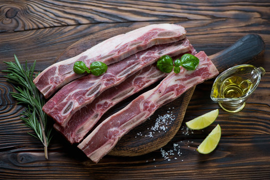 Raw fresh beef ribs and seasonings in a rustic wooden setting