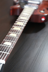 Brown electric guitar on black wooden background