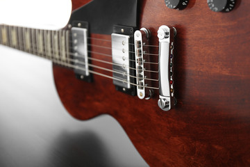Fototapeta na wymiar Brown electric guitar on black wooden background, close up