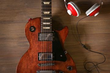 Brown electric guitar with headphones on wooden background