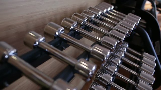 Set of metal dumbbell lying in a row on the stand horizontally