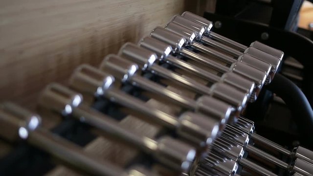Set of metal dumbbell lying in a row on the stand horizontally