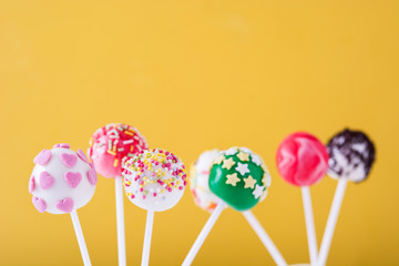 Sweet cake pops on yellow background

