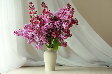 Bouquet of purple lilac flowers on white curtain background