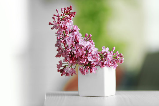 Purple lilac flowers in a vase on blurred background