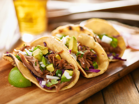 tasty mexican carnitas tacos with red cabbage, avocado, onion and cilantro