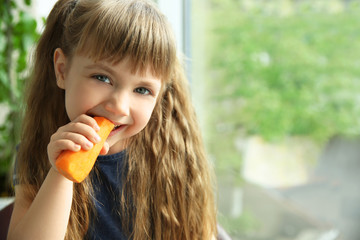 Little girl with carrot on window background