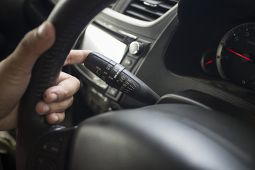 Fototapeta na wymiar The Finger Push a wiper control button on the car steering wheel