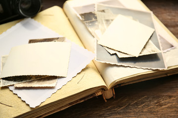 Album with vintage photos and camera on wooden background