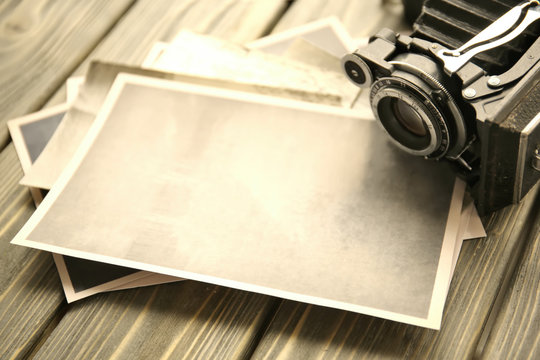 Vintage photos with camera on wooden background