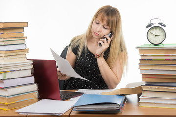 Teacher discusses by phone written on a sheet of paper