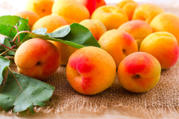 Fototapeta na wymiar Organic apricots with leaves on sacking background