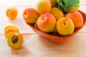 Organic apricots with leaves on wooden background