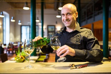 Waiter pouring white wine into glass