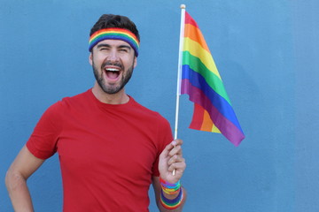 Fun homosexual male superhero standing with hand holding the gay flag 