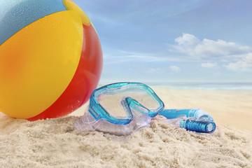 Beach ball and goggles in the sand