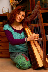 girl harpist in ethno outfit playing her instrument.