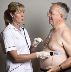 ENGLAND UK - JUNE 2016 - Member of a hospial cardiac measurement team installing a ambulatory ECG monitor to an overweight male patient