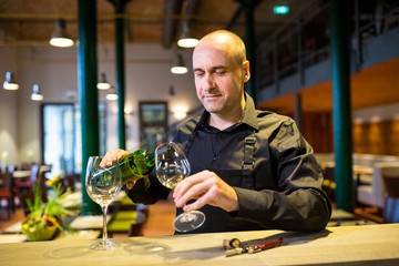 Waiter pouring white wine into glass