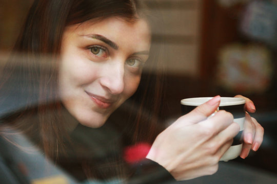 Young happy girl in cafe, view through a window