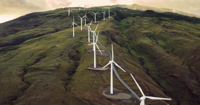 Aerial view of windmills turning at sunset, wind power turbines generate clean renewable energy