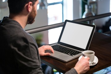 Man holding coffee cup and using laptop